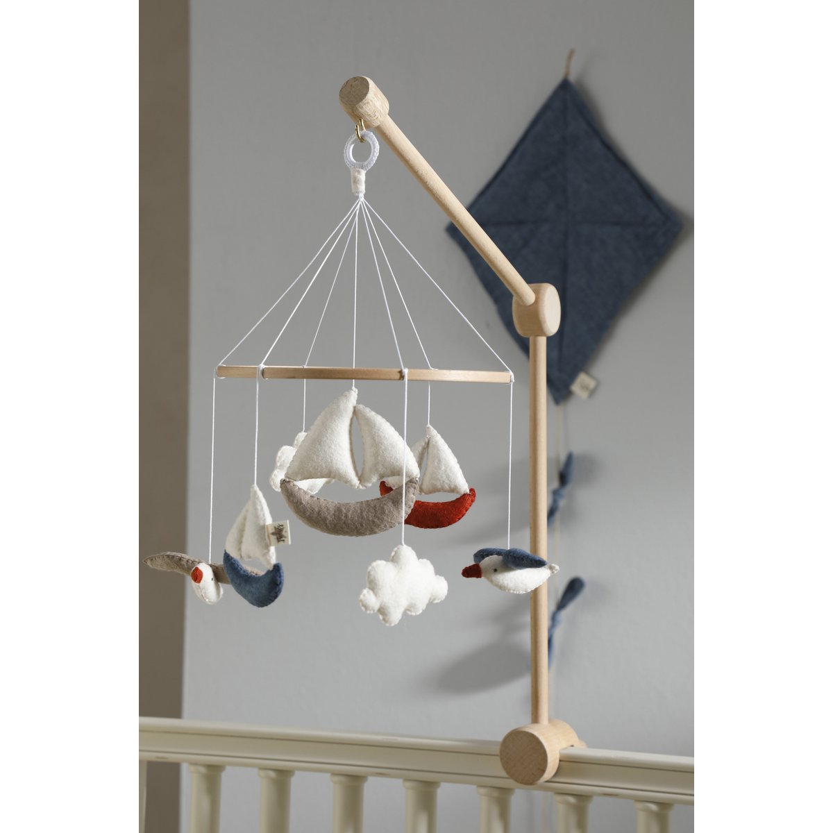 Handgefertigtes Baby-Mobile MARINA von 2 Stories aus Filz mit maritimen Motiven: drei Boote in Weiß, Blau und Rot, zwei Möwen und zwei Wolken in sanften Beige- und Blautönen – liebevoll gestaltet für das Babybett.