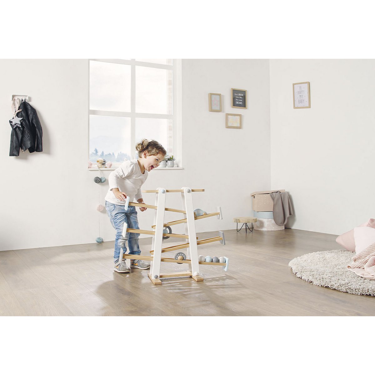 Kleinkind spielt im Kinderzimmer mit Kugelbahn 'Kuno' aus Holz, mit bunten Bahnen und rollenden Kugeln, fördert Motorik und Koordination von Kleinkindern