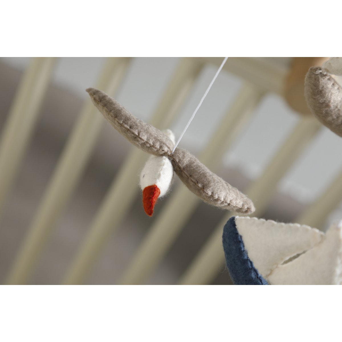 Detailaufnahme der weißen Filz-Möwe aus dem MARINA Mobile von 2 Stories – mit grauen Flügeln, rotem Schnabel und liebevoll handgearbeiteten Nähten.