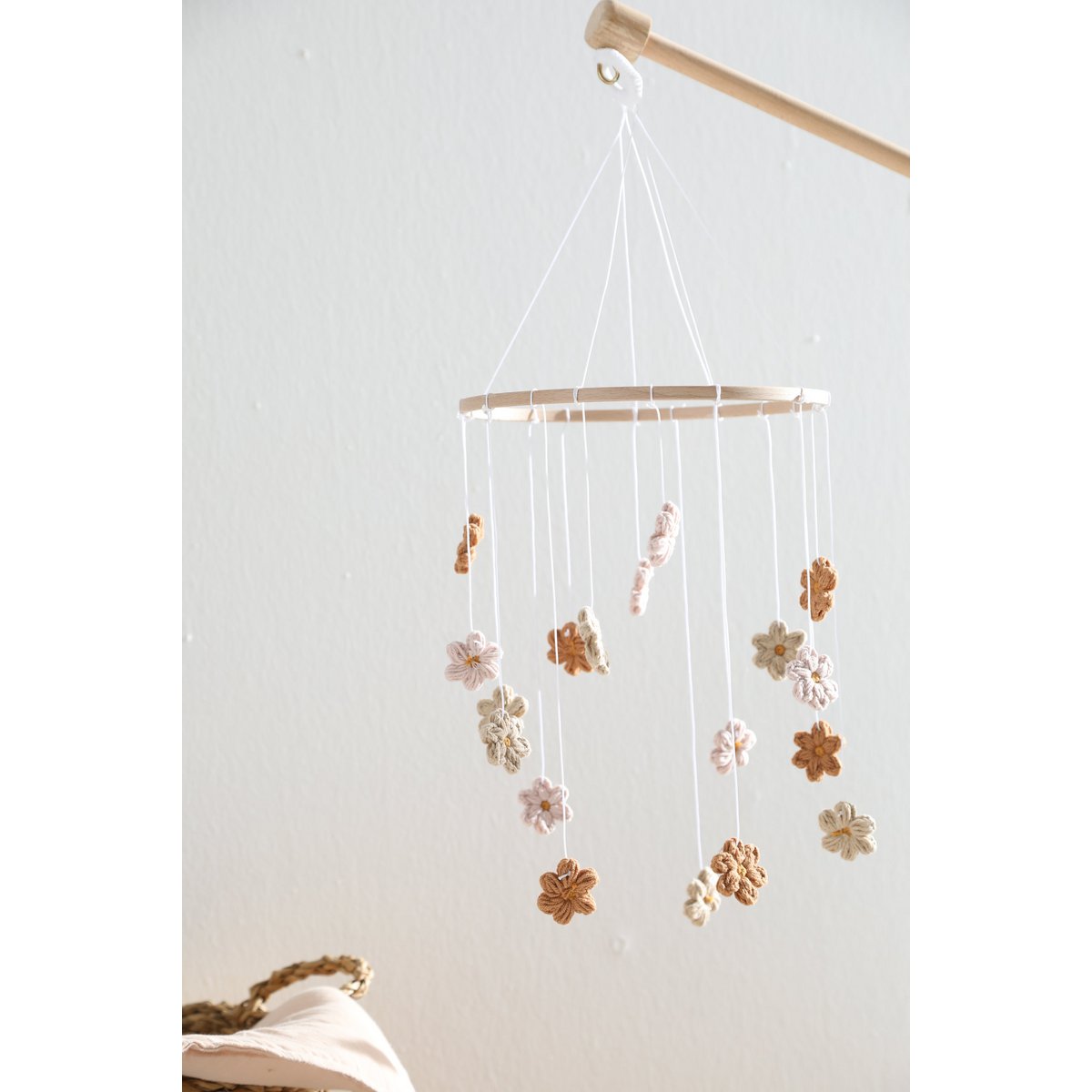 Sanftes Baby-Mobile HIMMELBLOM von 2 Stories aus Baumwolle und Holz – zarte Blüten in Beige und Rosa hängen an einem Holzring und drehen sich ruhig über dem Babybett. Die handgearbeiteten Blumen sorgen für eine beruhigende, natürliche Atmosphäre im Kinderzimmer.