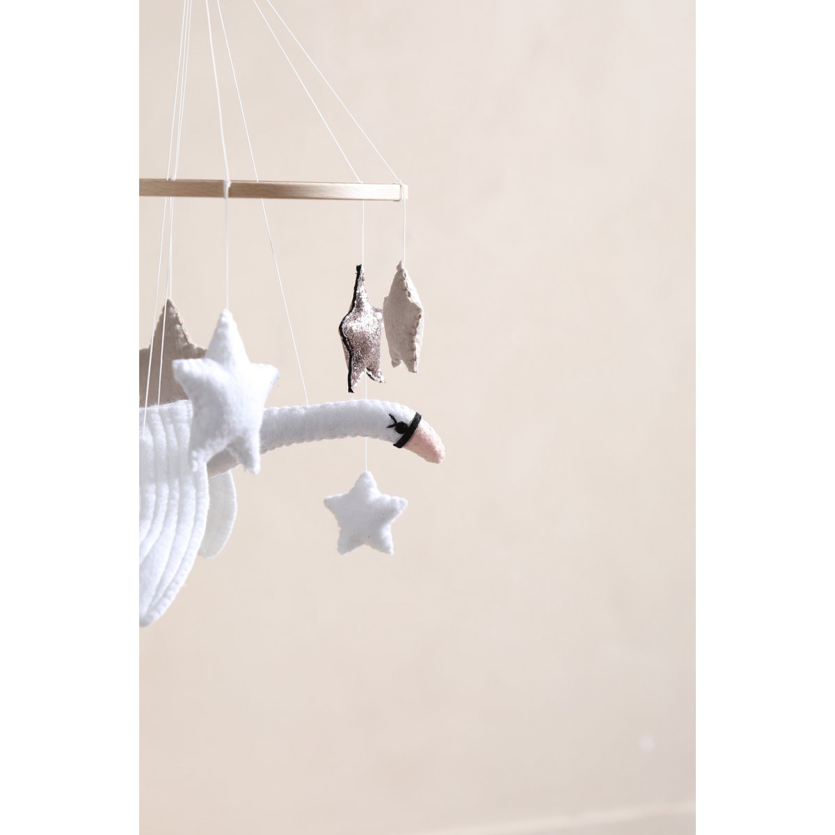 Filz-Mobile für das Babybett mit einem weißen Schwan und sieben schwebenden Sternen in Weiß, Beige und Bronze – stilvolle und beruhigende Deko fürs Babyzimmer.