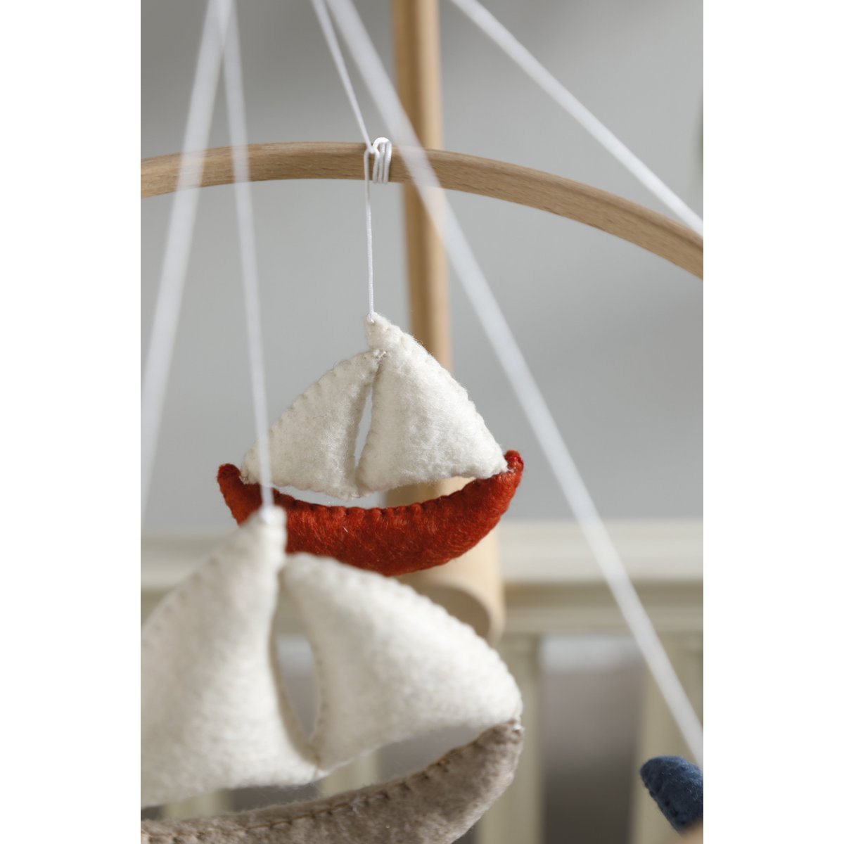 Detailansicht des beigefarbenen Filzboots aus dem MARINA Mobile von 2 Stories – mit handgenähten Nähten und weißem Segel, liebevoll verarbeitet
