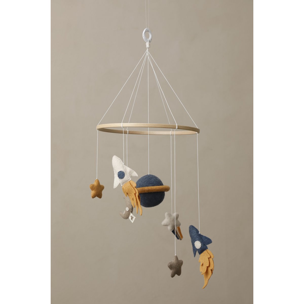 SPACE Baby-Mobile von 2 Stories aus Filz und Holz – mit zwei Raketen (blau und weiß) mit Feuerschweif, einem blauen Saturn in der Mitte, einem weißen Stern mit Schweif, grauem Mond sowie einem gelben und einem weißen Stern – in sanften Beige-, Blau- und Grautönen.