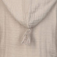 Bild in Galerie-Betrachter laden, Detailaufnahme einer beigen Musselin-Kapuzenjacke oder eines Bademantels für Kinder. Die Kapuze hat eine dekorative Quaste an der Spitze. Das Material ist weich und leicht strukturiert.
