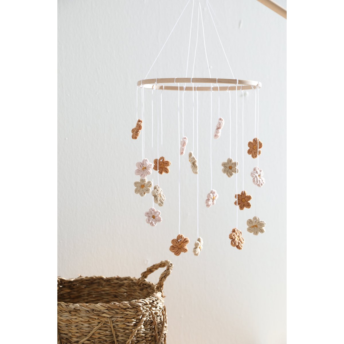 Sanftes Baby-Mobile HIMMELBLOM von 2 Stories aus Baumwolle und Holz – zarte Blüten in Beige und Rosa hängen an einem Holzring und drehen sich ruhig über dem Babybett. Die handgearbeiteten Blumen sorgen für eine beruhigende, natürliche Atmosphäre im Kinderzimmer.