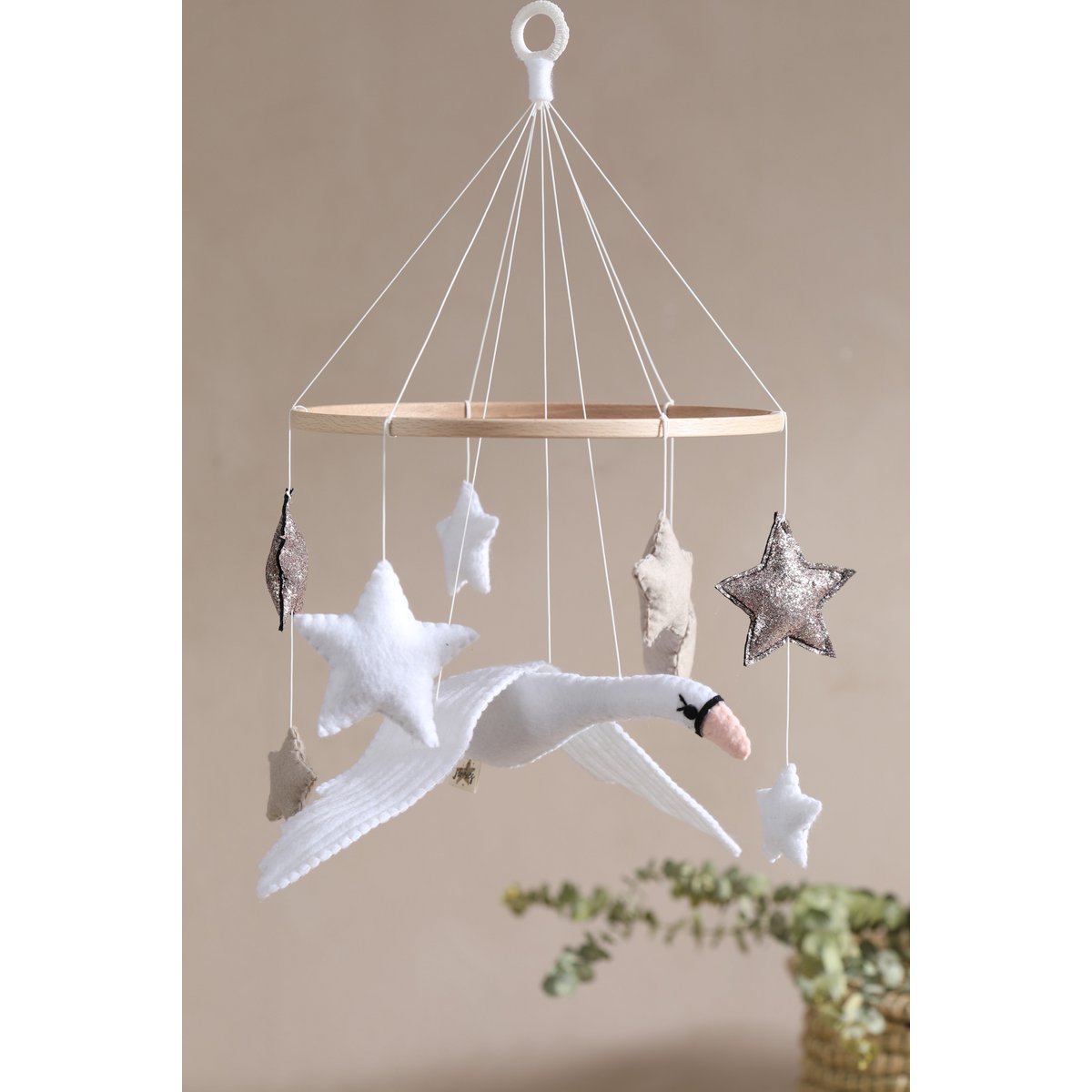 Filz-Mobile für das Babybett mit einem weißen Schwan und sieben schwebenden Sternen in Weiß, Beige und Bronze – stilvolle und beruhigende Deko fürs Babyzimmer.