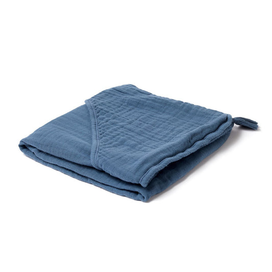 Zusammengelegtes, blaues Kapuzenhandtuch aus weichem BBio Baumwoll-Musselin. Die Spitze der Kopfbedeckung ziert eine blaue Quaste im selben Farbton.