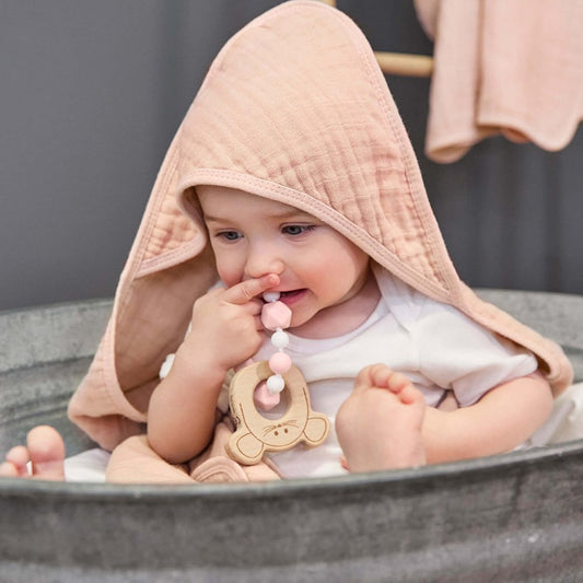Kleinkind sitzt nuckelnd an einer Schnullerkette in einer Zinkbadewanne ,umhüllt vom weichen Kaputzenhandtuch 