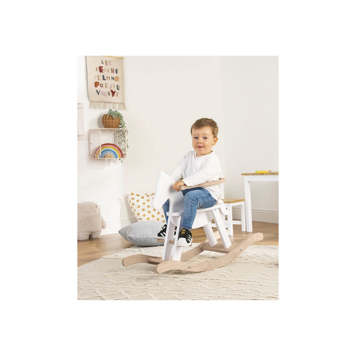 Kind Schaukelt auf dem Schaukelpferd 'Pinolino' in Weiß und Naturholz, mit Sicherheitsring, für sicheren Schaukelspaß im Kinderzimmer