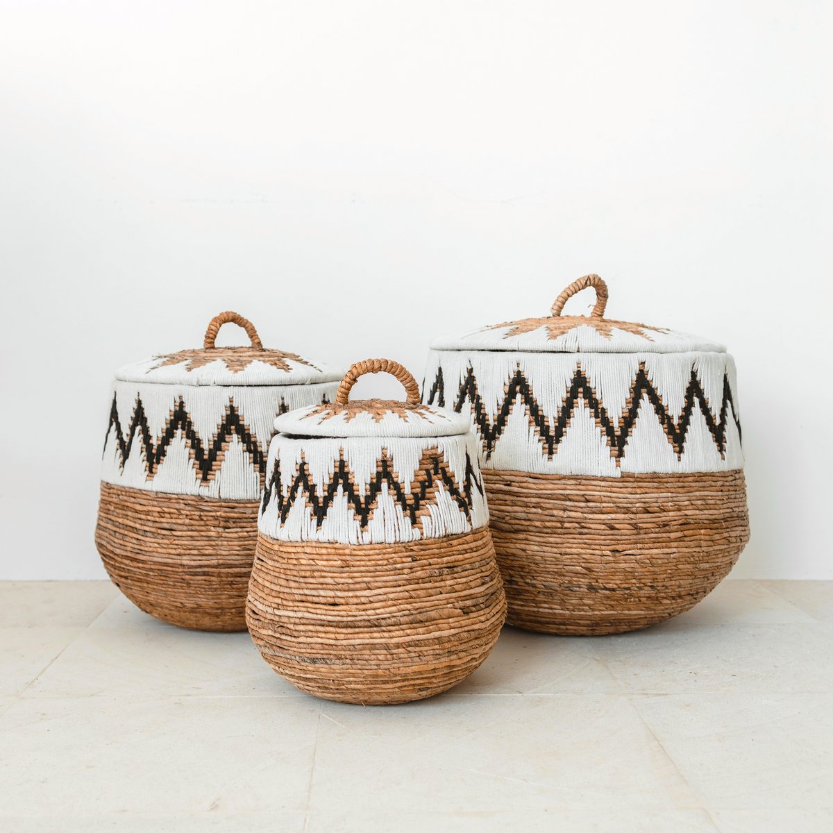Drei runde Wäschekörbe mit Deckel im Boho-Stil, handgeflochten mit dekorativem Baumwollmuster – Modell PAL, ideal zur stilvollen Aufbewahrung im Kinderzimmer. Maße: 43x45cm, 33x40cm und 55x50cm