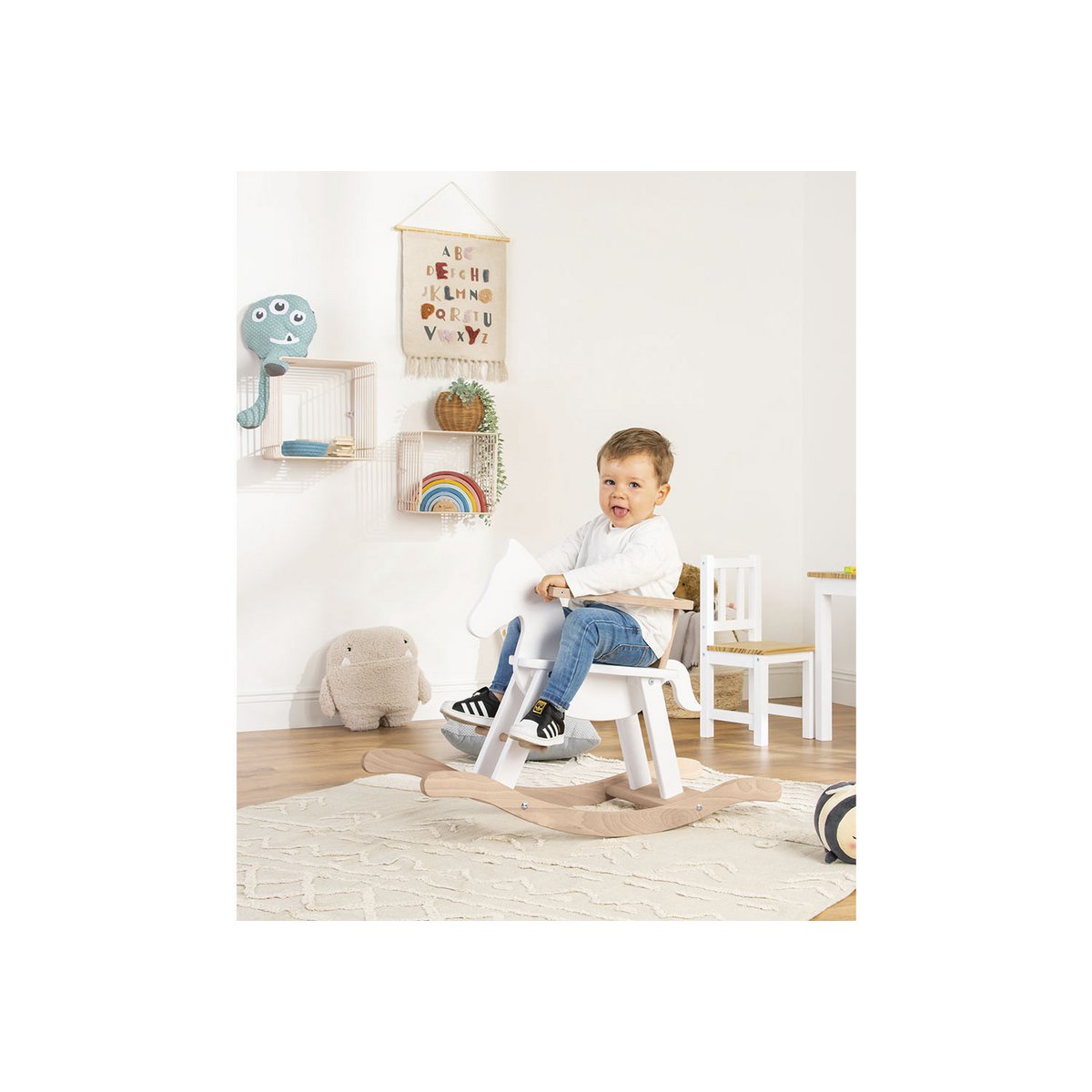 Kind schaukelt audf dem Schaukelpferd 'Pinolino' in Weiß und Naturholz, mit Sicherheitsring, für sicheren Schaukelspaß im Kinderzimmer