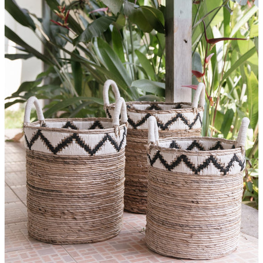 „Korb DALU aus natürlicher Bananenfaser, handgeflochten im Boho-Stil, vielseitig einsetzbar als Wäschekorb, Aufbewahrung oder Pflanzkorb – erhältlich in drei Größen. Der obere Rand ziert ein zickzack Muster in beige und dunkelbraun.